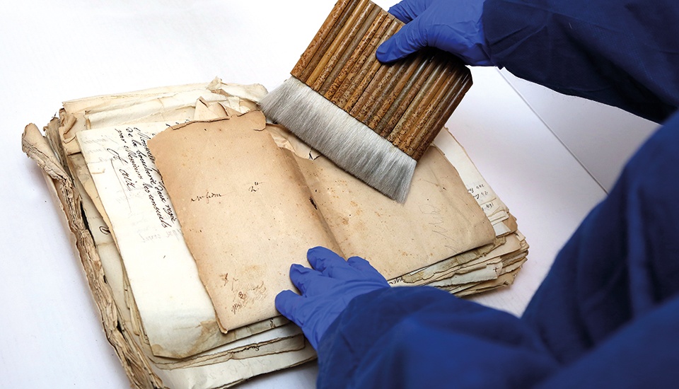 Dépoussierage avec brosse manuelle sur livre et manuscrit ancien